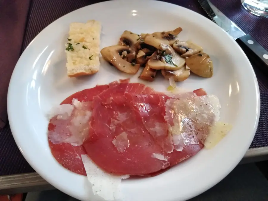 Bord met rundercarpaccio, parmezaanse kaas, champignons en focaccia
