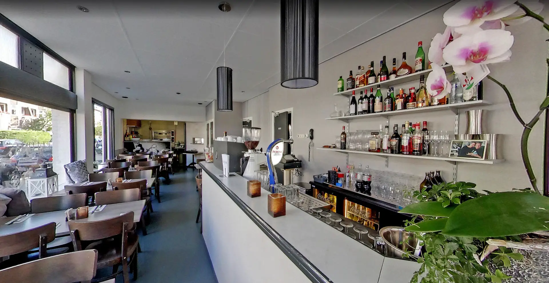 Het restaurant van La Luna: de bar met flessen, tafels langs het raam en een orchidee